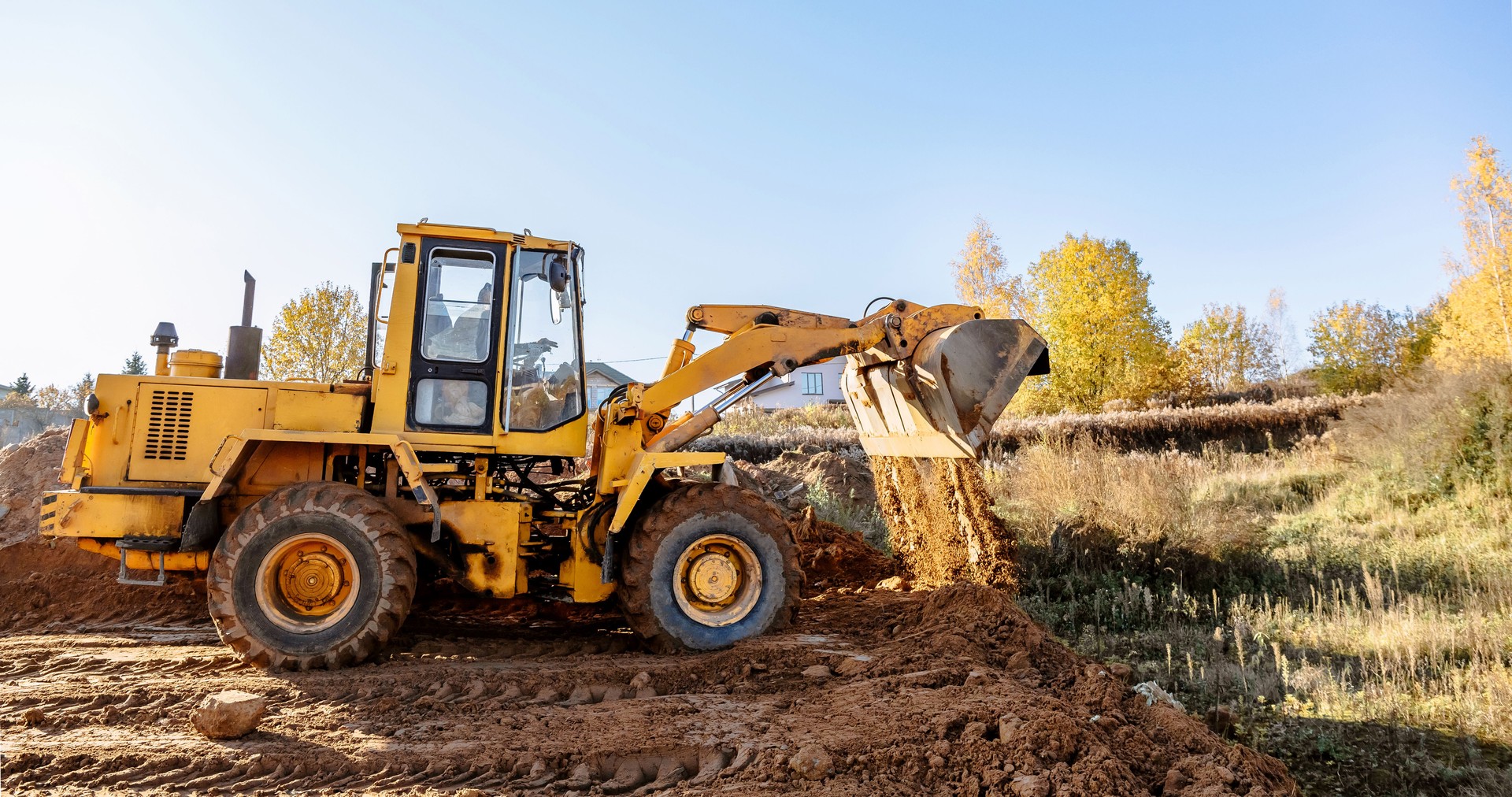 large yellow wheel loader aligns a piece of land for a new building. Preparation of the land for the auction. Leveling the landscape and adding sand for construction.